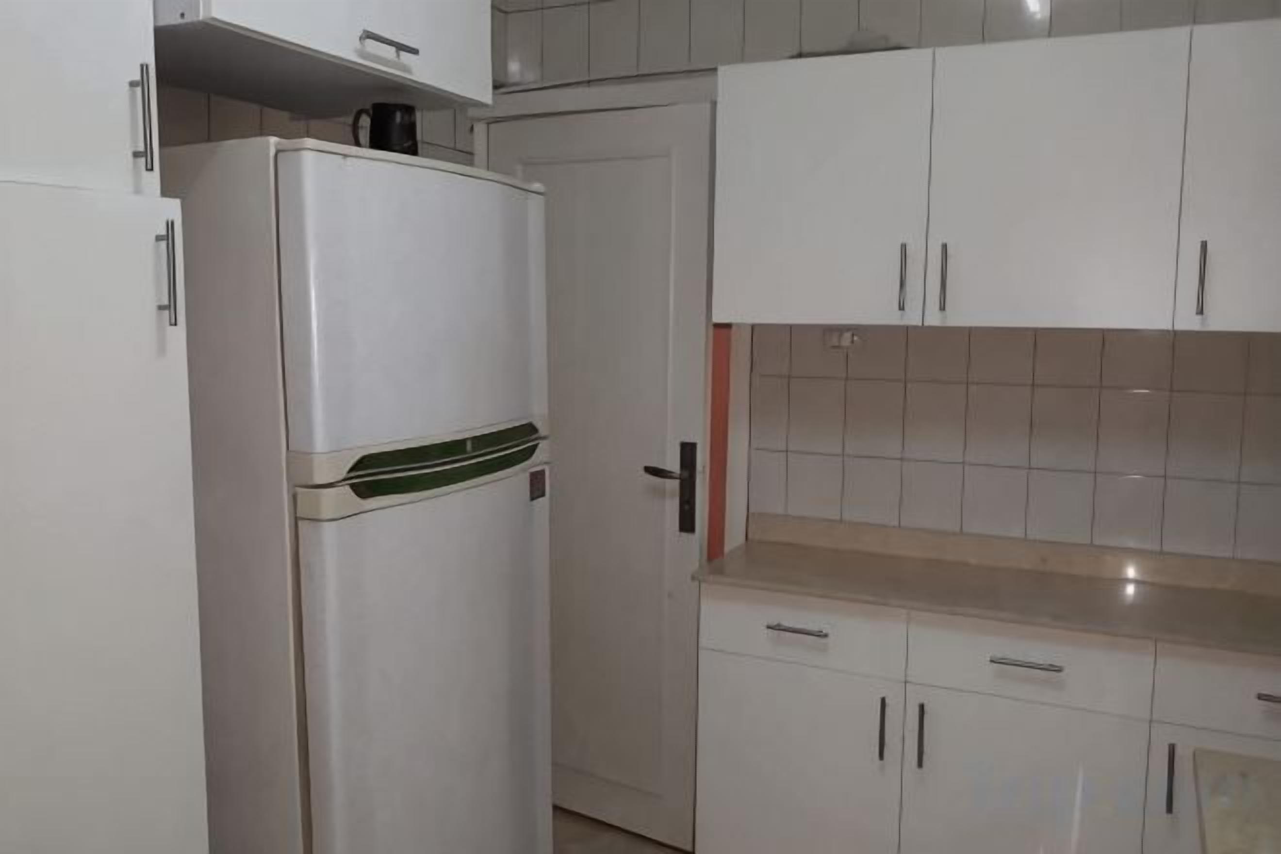 A kitchen with white cabinets, a white refrigerator, and a tiled backsplash.