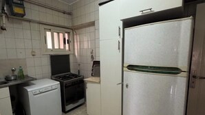 A compact kitchen with a dishwasher, stove, oven, and a refrigerator. - Jessy Residential Apartment (Cairo)