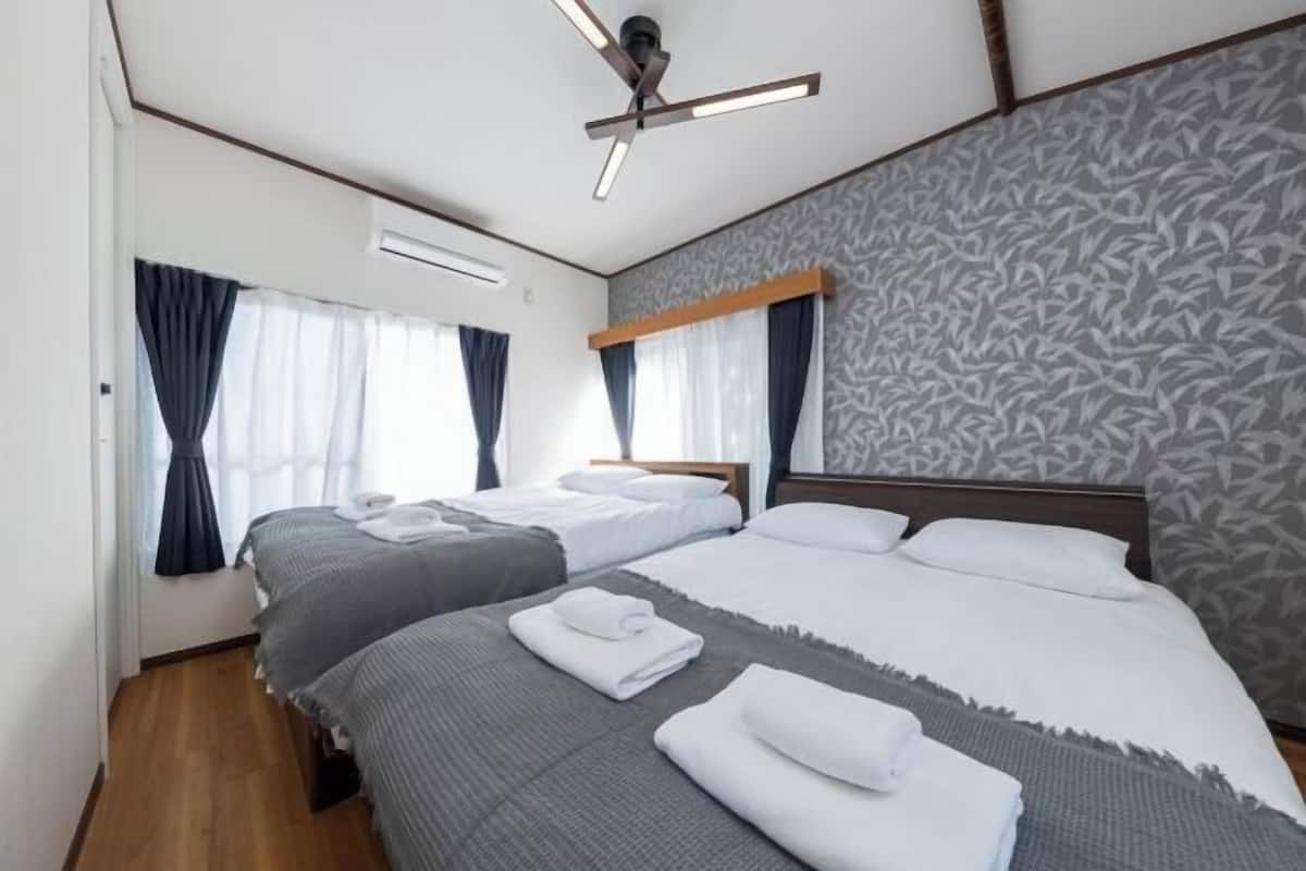 A hotel room with two beds, a ceiling fan, and patterned wallpaper.
