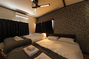 A hotel room with two beds, a ceiling fan, and a patterned wall. - Ikebukuro 15min|Family House|8Guests (Tokyo)