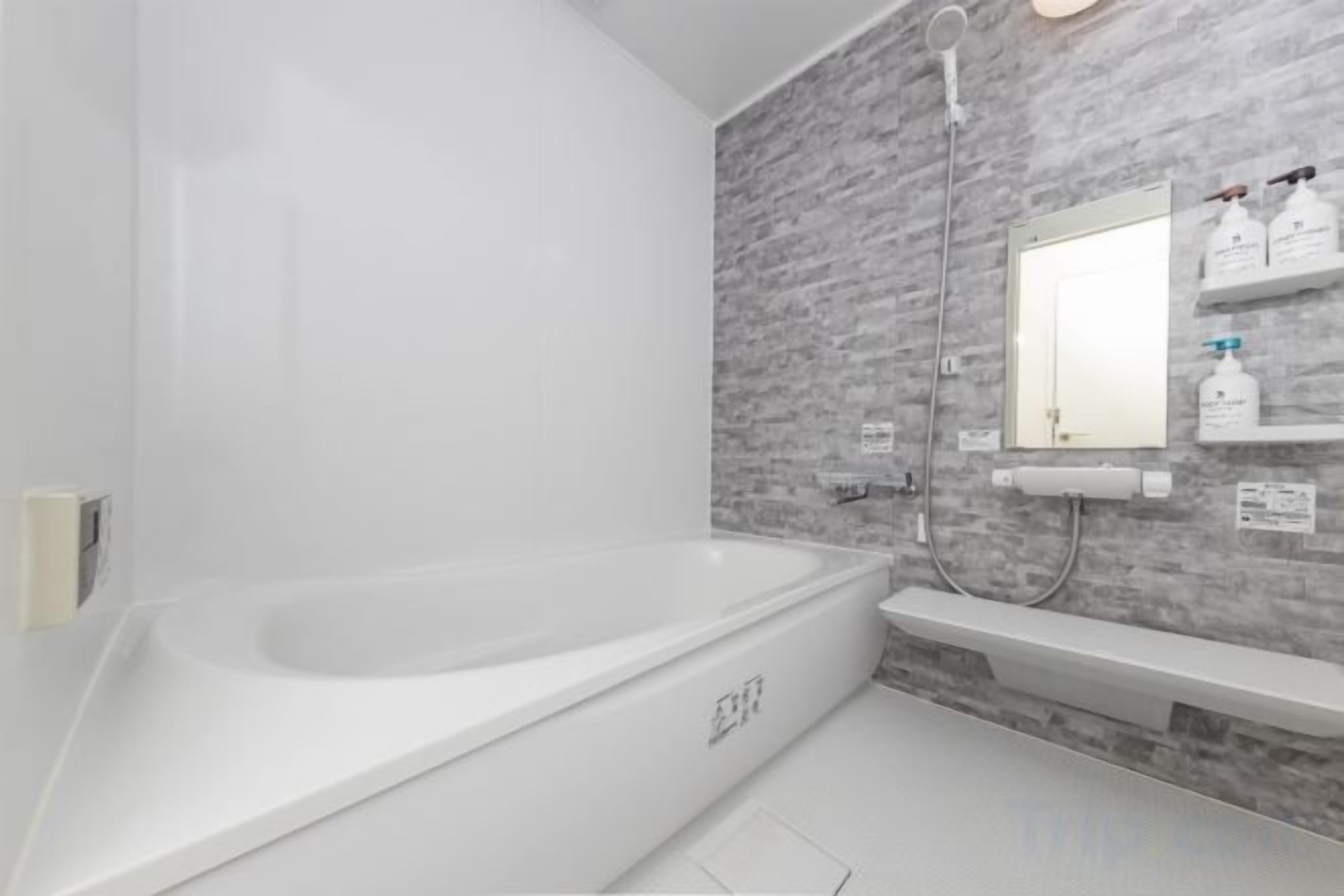 Un bagno moderno con una vasca freestanding, uno specchio fissato alla parete e uno scaffale con articoli da toilette.