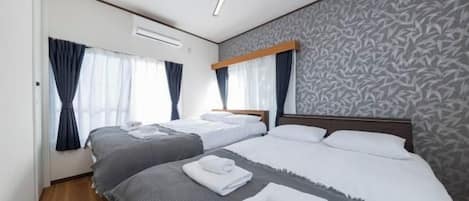 A hotel room with two beds, a ceiling fan, and a patterned wall.