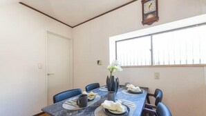 A dining area with a marble table, blue chairs, a vase with flowers, and a clock on the wall. - Ikebukuro 15min｜Family House｜8Guests (Tokyo)