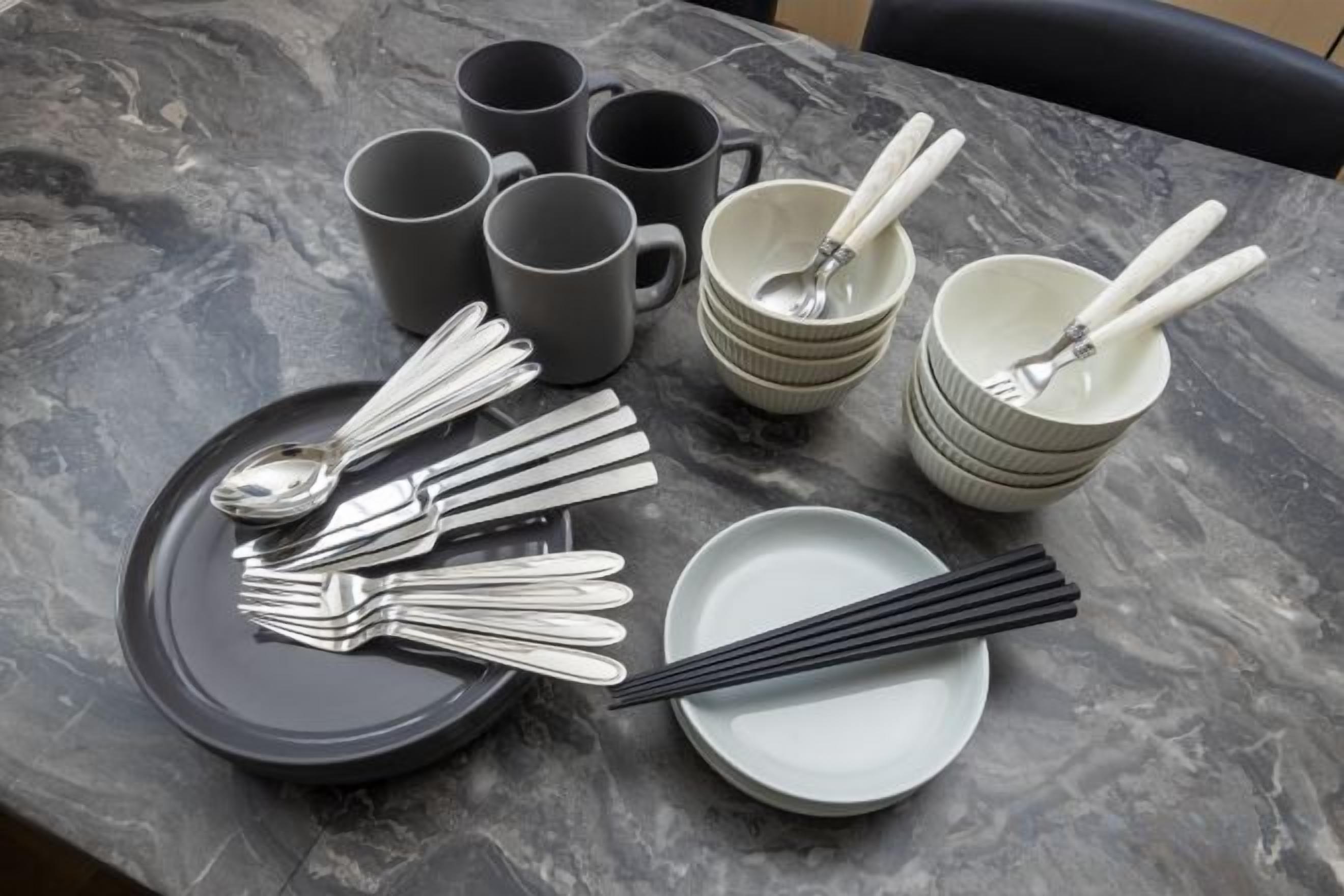 A table set with various utensils and dishes, including forks, spoons, and bowls.