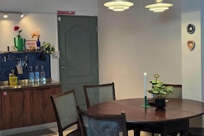 A dining area with a round table, chairs, a bar area with a sign, and a door marked 'Dramatic Exit'. - W. House for group, Cozy Loft near Suvarnabhumi Airport (Bangkok)