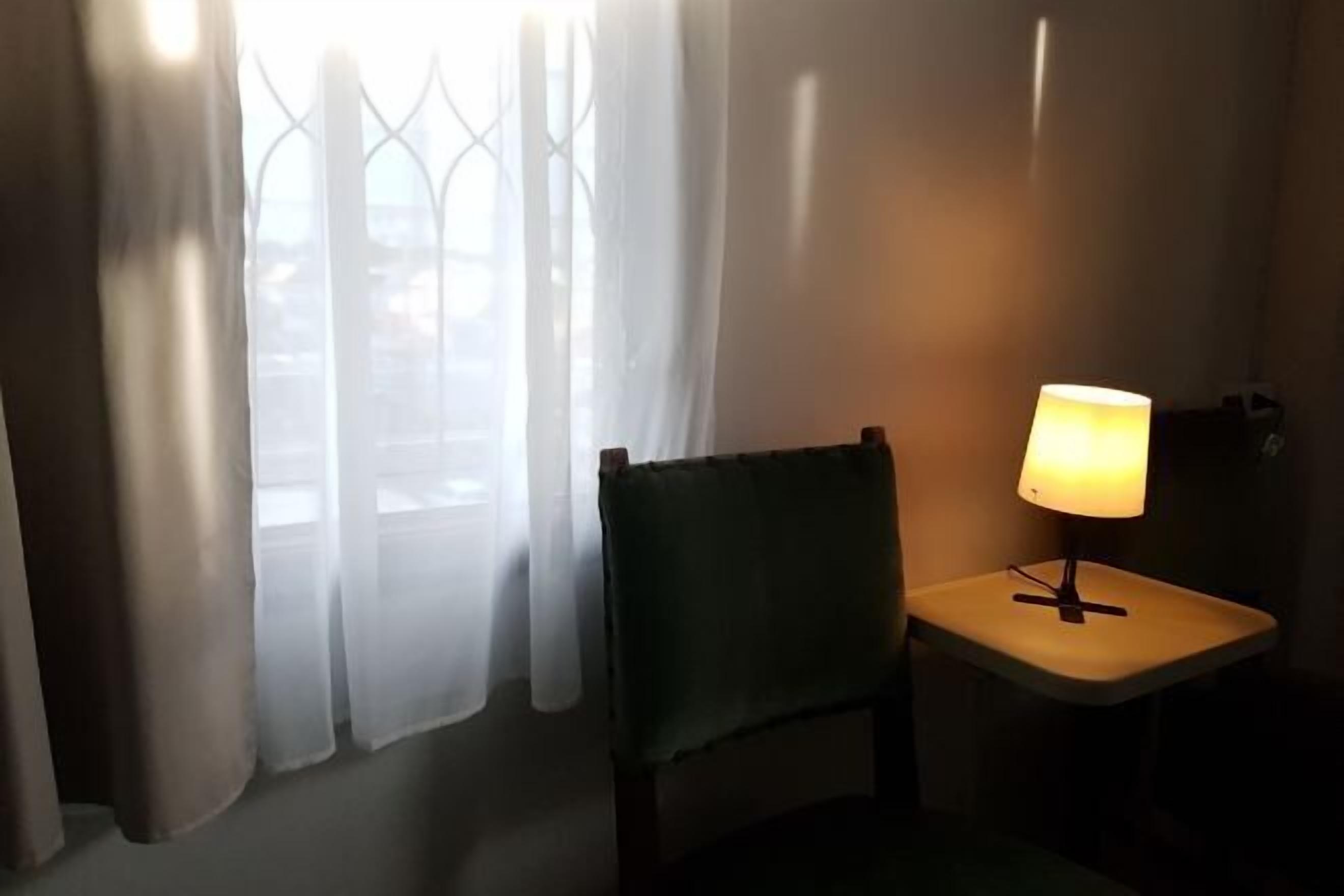 A room with a chair and a table with a lamp.