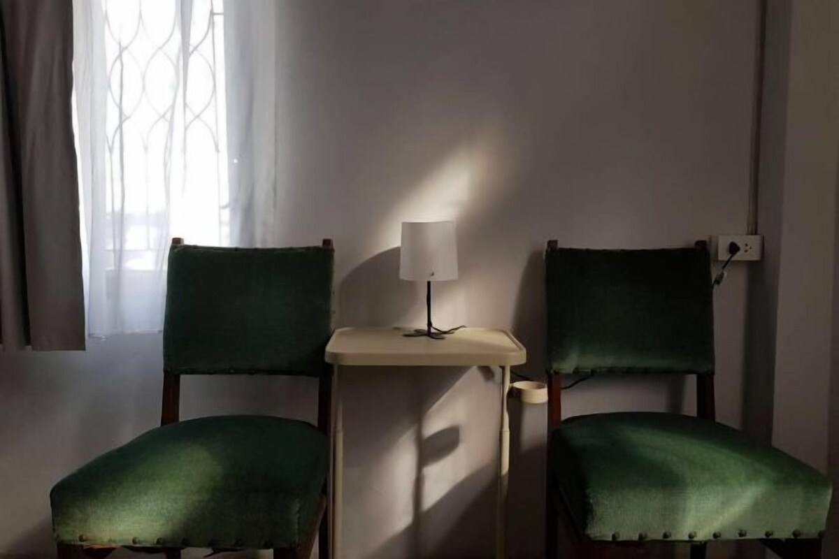 Une pièce avec deux fauteuils verts et une petite table sur laquelle se trouve une lampe.