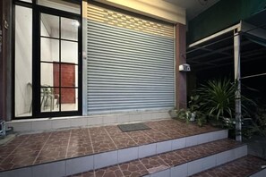 A closed garage door, a set of steps leading to a door, and a potted plant. - W. House for group, Cozy Loft near Suvarnabhumi Airport (Bangkok)