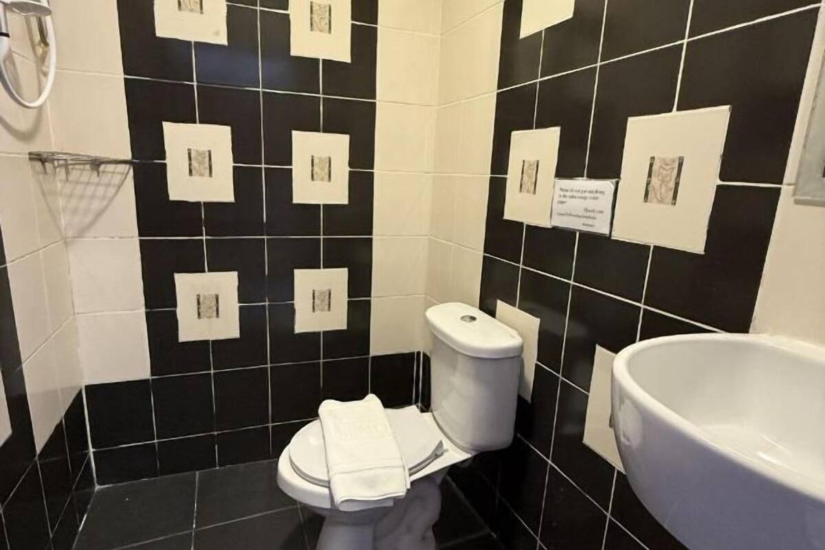 A bathroom with black and white tiles, a toilet, a sink, and a towel rack.