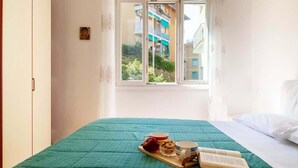 Ein Schlafzimmer mit Bett, Fenster und Blick auf Gebäude.