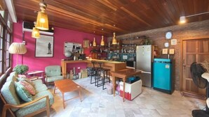 A cozy living area with a wooden ceiling, a kitchen with a blue refrigerator, and a bar area. - T-House BKK 2floors near BTS with Swimming pool and Free Wifi (Bangkok)