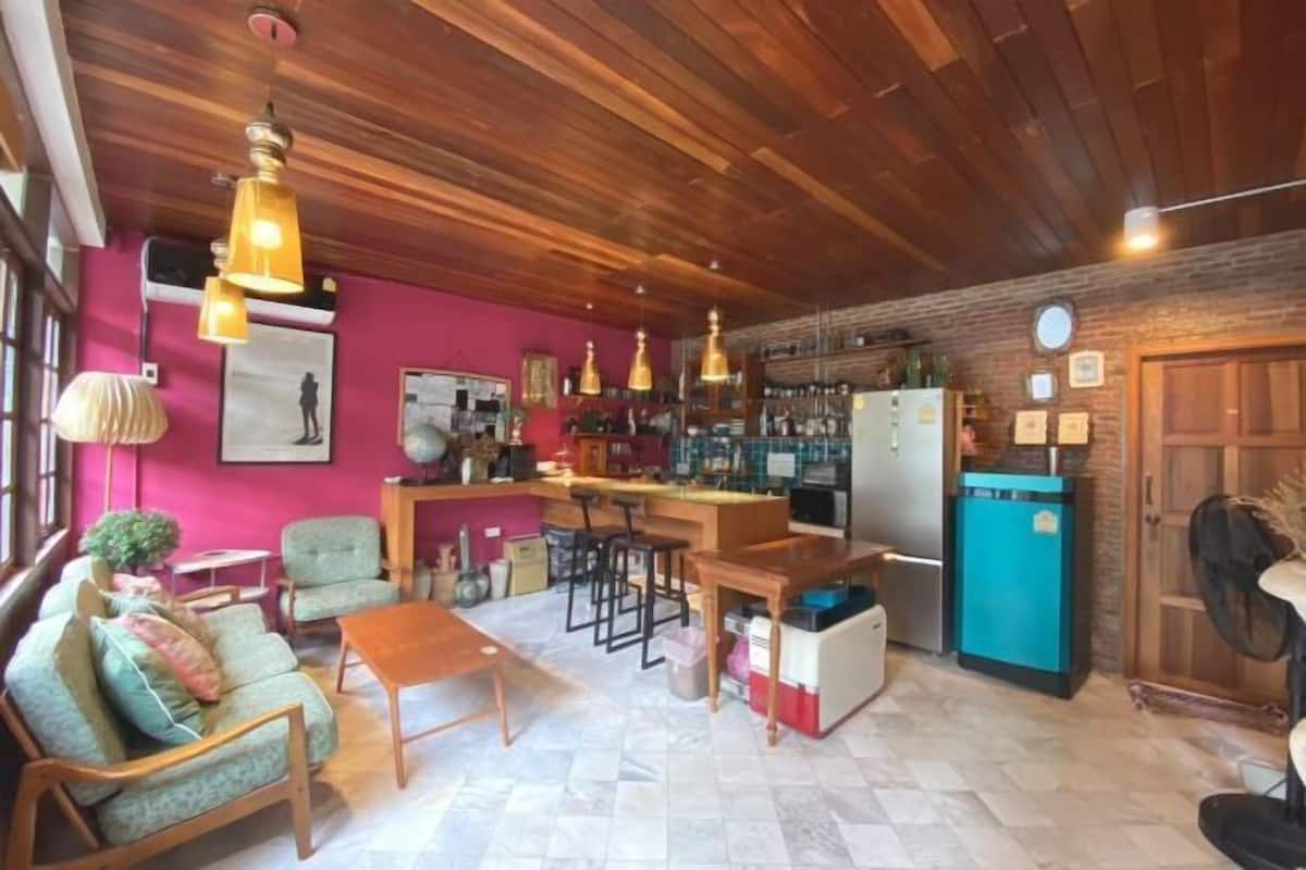 A cozy living area with a wooden ceiling, a kitchen with a blue refrigerator, and a bar area.