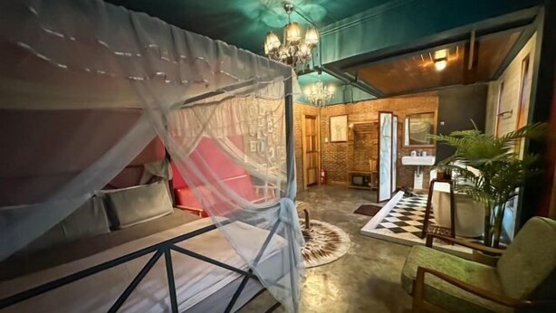 A room with a bed covered by a white canopy, a staircase leading to another room, a chandelier, and a checkered floor. - T-House BKK 2floors near BTS with Swimming pool and Free Wifi (Bangkok)
