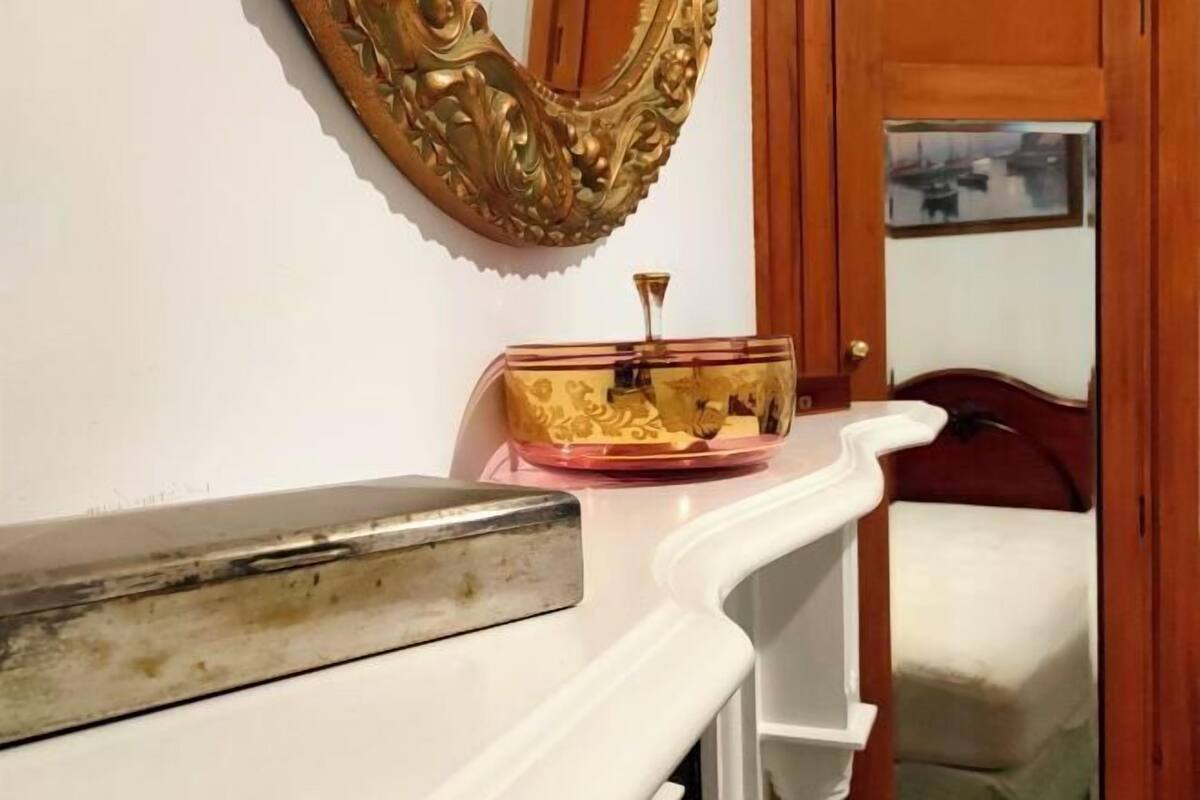 A room with a white bench, a decorative mirror, and a small table with a glass top.