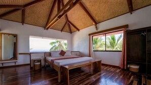 Een kamer met een bed, een raam, een spiegel en uitzicht op palmbomen.