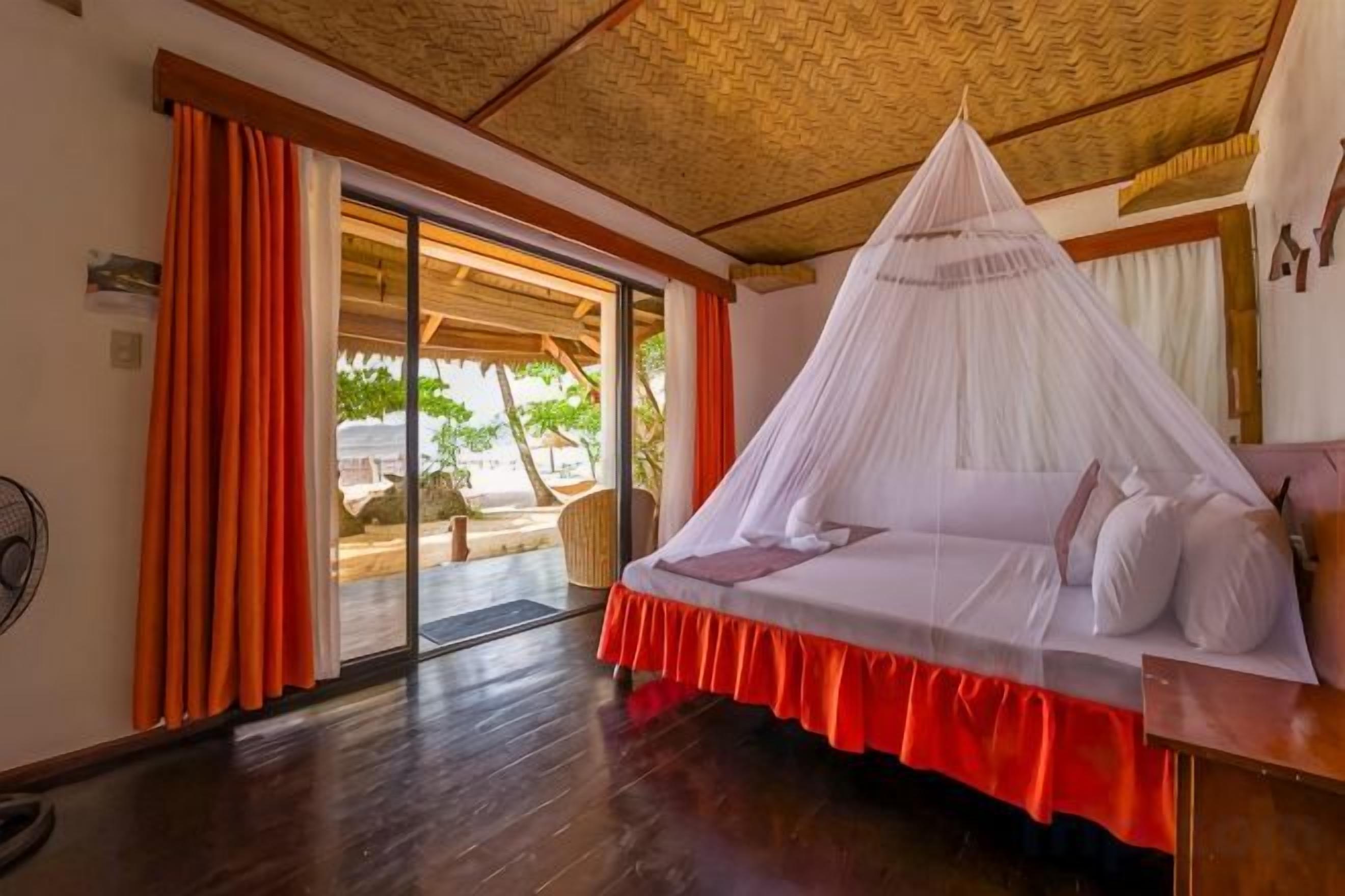 A room with a bed, a fan, and a view through a glass door.