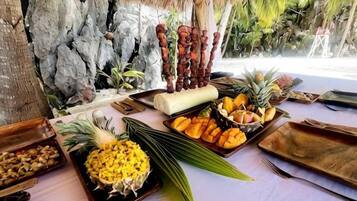 A table with various food items and a thatched roof structure.