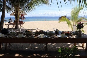 Een restaurant aan het strand, met een tafel voor twee, met uitzicht op de oceaan.
