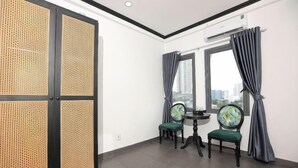 A room with a large window, two chairs, a small table, and a traditional screen door. - Phu Gia Hotel 228 Le Van Luong (Ho Chi Minh City)