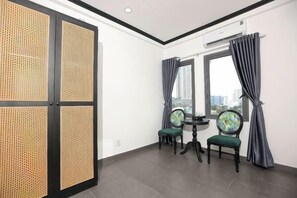 A room with a large window, two chairs, a small table, and a traditional screen door.