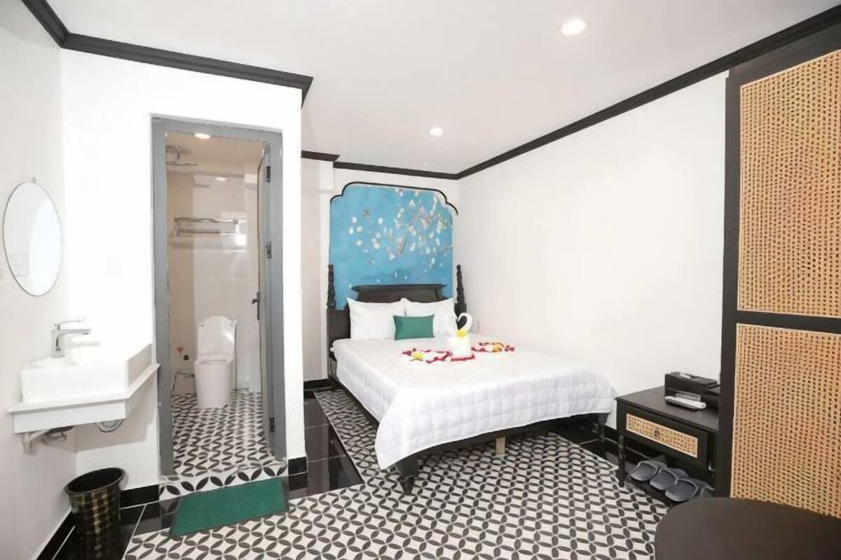 A hotel room with a bed, a bathroom, and a small seating area.