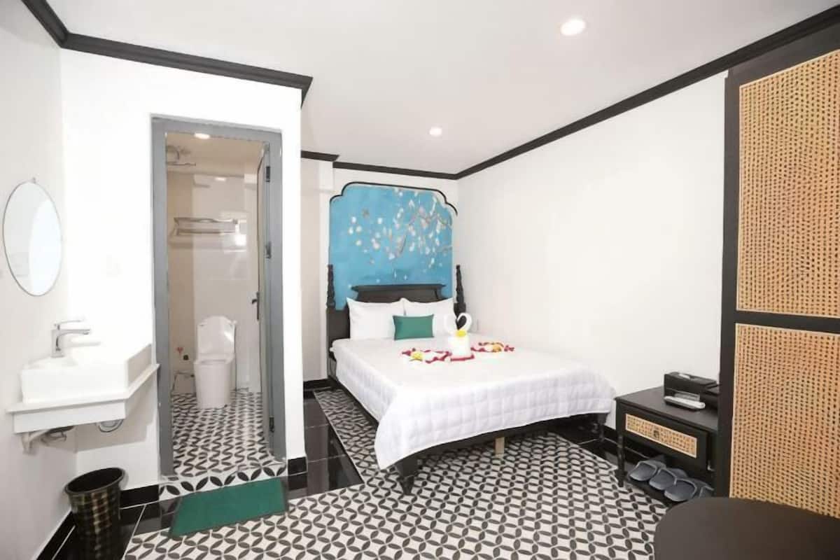 A hotel room with a bed, a bathroom, and a small seating area.