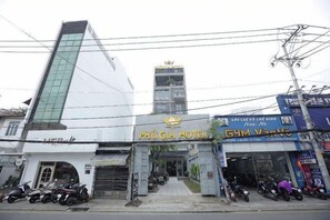 A hotel with a prominent vertical glass facade, a gym, and several parked motorcycles. - Phu Gia Hotel 228 Le Van Luong (Ho Chi Minh City)