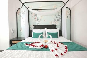 A bed with a canopy, two pillows, a green bedspread, and rose petals arranged on the bed. - Phu Gia Hotel 228 Le Van Luong (Ho Chi Minh City)
