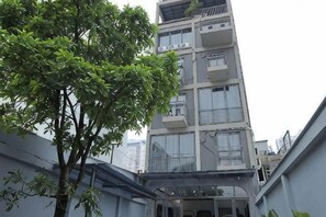 A multi-story building with balconies and a tree in the foreground. - Phu Gia Hotel 228 Le Van Luong (Ho Chi Minh City)