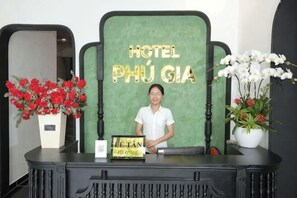 A reception desk with a sign reading 'HOTEL PHÚ GIÁ' and a person seated behind it.