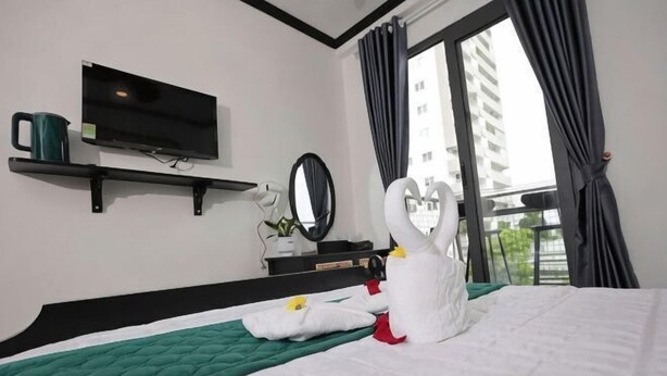 A hotel room with a bed, a flat-screen TV, a mirror, and a window with curtains. - Phu Gia Hotel 228 Le Van Luong (Ho Chi Minh City)