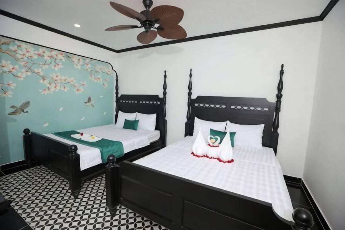 A room with two black four-poster beds, a ceiling fan, and a patterned floor.