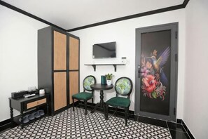 A room with a black and white patterned floor, a green sofa, a small table with a plant, a wall-mounted TV, and a decorative painting. - Phu Gia Hotel 228 Le Van Luong (Ho Chi Minh City)