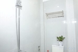 A bathroom with a shower, a toilet, and a small potted plant. - Phu Gia Hotel 228 Le Van Luong (Ho Chi Minh City)