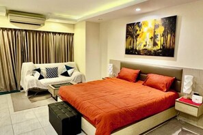 A hotel room with a bed, a sofa, a nightstand, an air conditioner, and a painting on the wall. - View talay 6, city center, next to central mall, direct access to the beach (Pattaya)