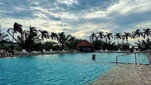 A swimming pool with lounge chairs and palm trees. - View talay 6, city center, next to central mall, direct access to the beach (Pattaya)