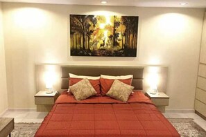 A bedroom with a large bed, two bedside tables, a headboard, and a wall-mounted painting. - View talay 6, city center, next to central mall, direct access to the beach (Pattaya)