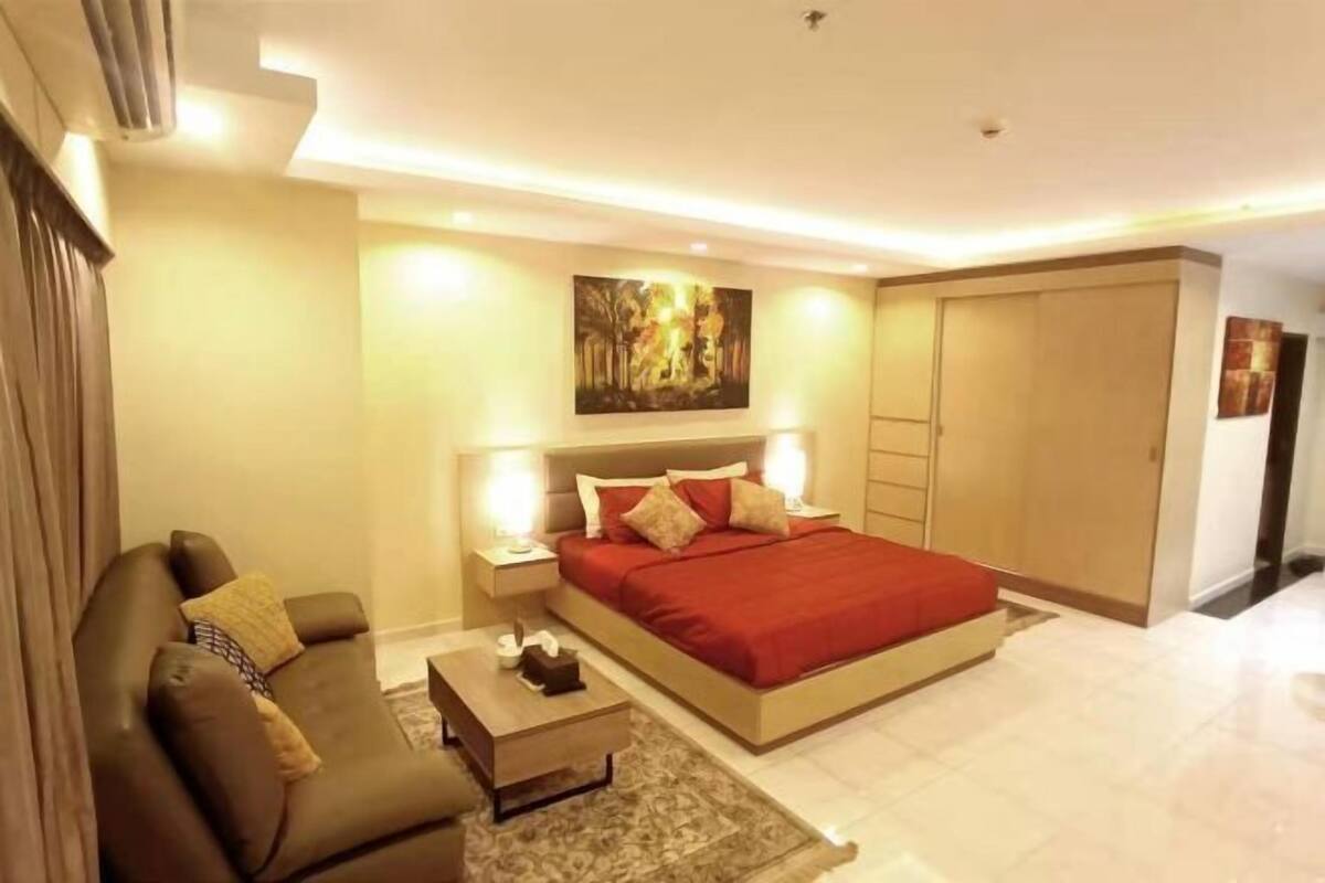A hotel room with a bed, nightstands, a sofa, a coffee table, and a painting on the wall.