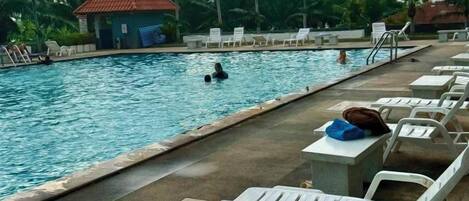 A swimming pool with lounge chairs and a small hut.
