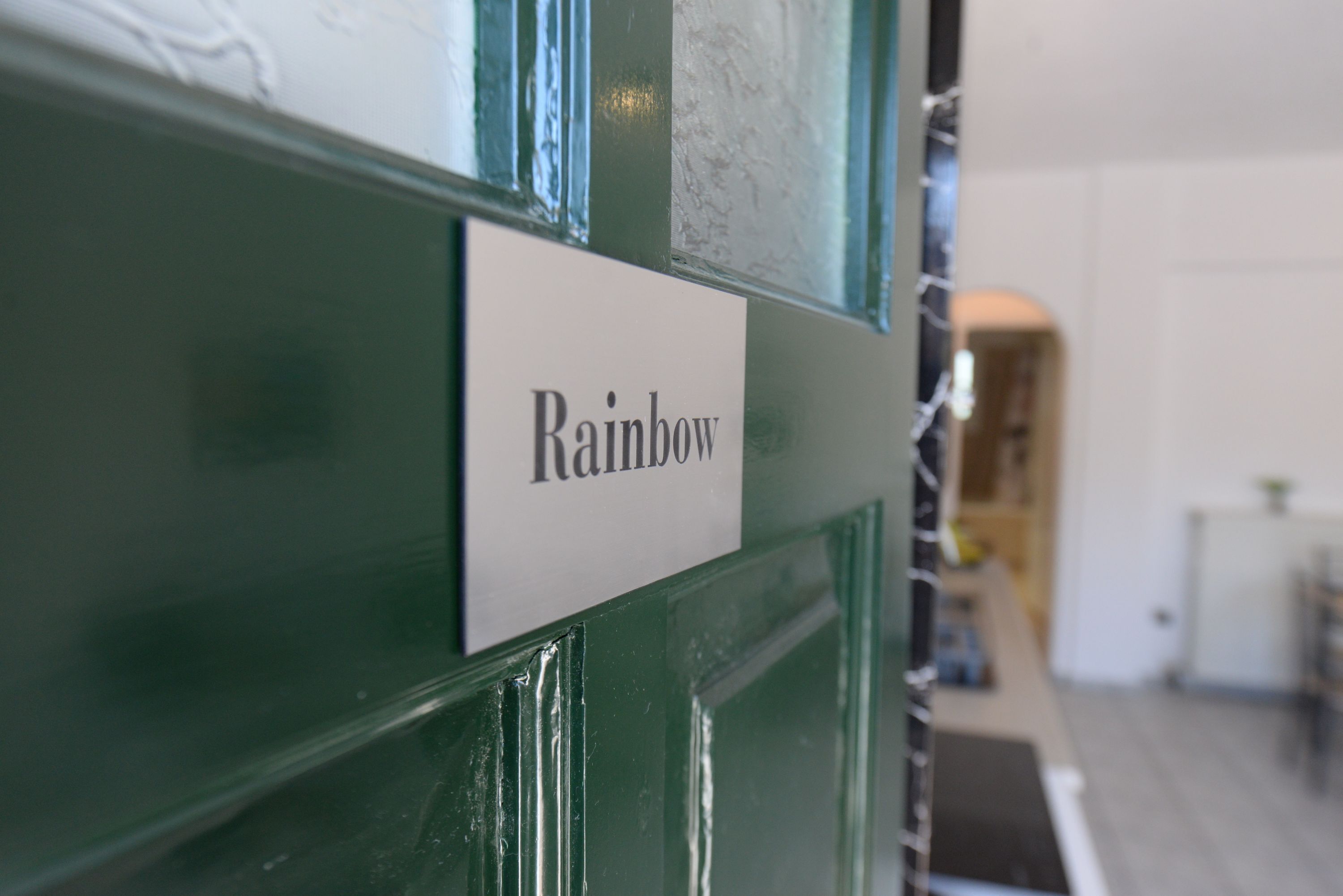 A close-up of a green wall with a sign that reads 'Rainbow.'