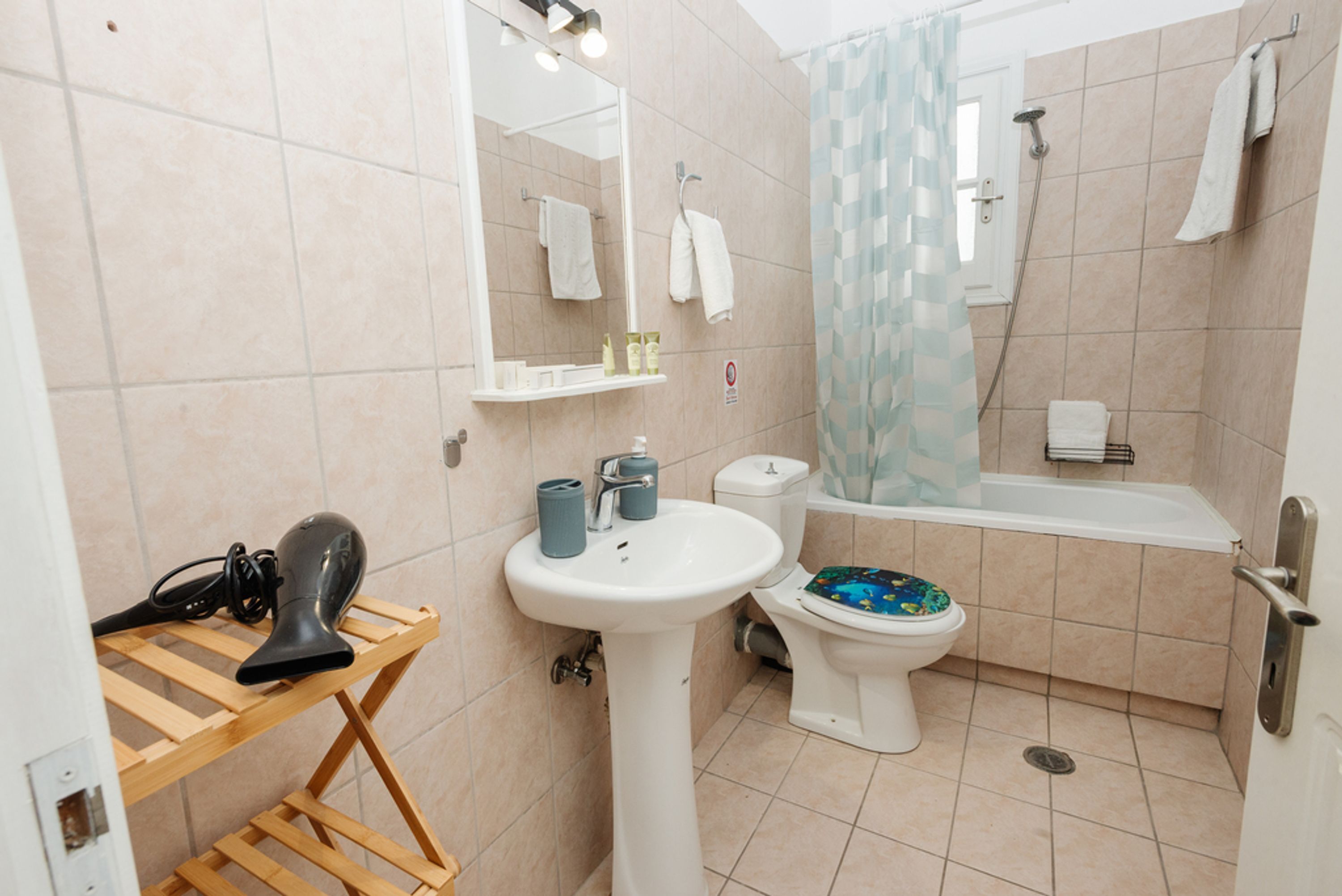A bathroom with a sink, toilet, shower, and a mirror.