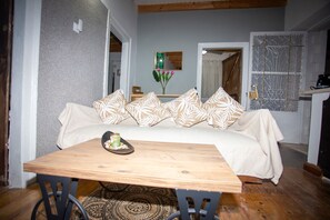 Ein gemütlicher Wohnbereich mit einer Couch, einem Holztisch und einem gemusterten Teppich.
