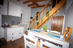A kitchen with white cabinets, a wooden staircase, and a dining table with chairs. - Archontissa House - Sea View (Corfu)