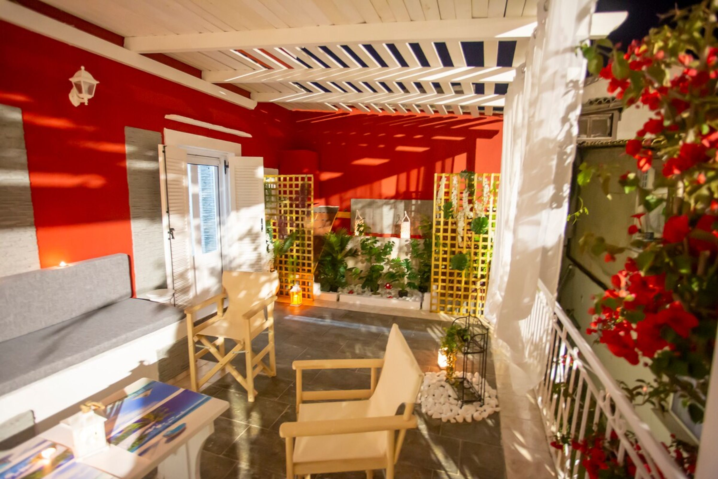 A cozy indoor seating area with a red and white color scheme, wooden furniture, and a decorative plant arrangement.