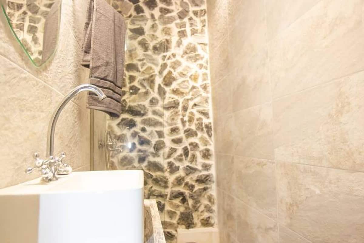 A bathroom with a stone wall, a white sink, and a toilet.