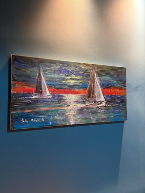 A painting of two sailboats on a body of water with a sunset or sunrise in the background.