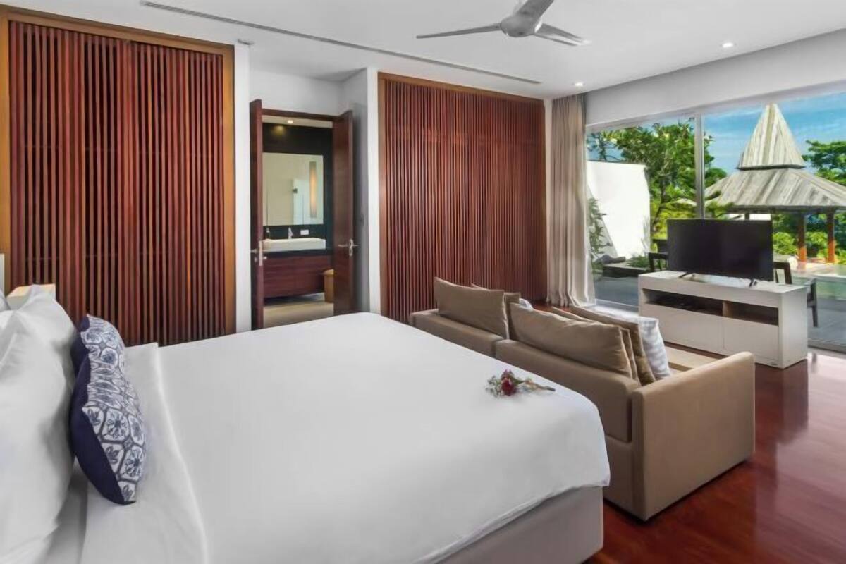 Une chambre d’hôtel moderne, dotée d’un grand lit, d’un canapé, d’une télévision et offrant une vue sur l’extérieur.