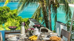 A breakfast table with a view of a turquoise sea and palm trees. - Laemsingh Villa 3 (Phuket)
