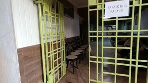 Une pièce avec une porte verte, une enseigne indiquant « PALAIS DE PARSIK HILL », et plusieurs tables rondes.