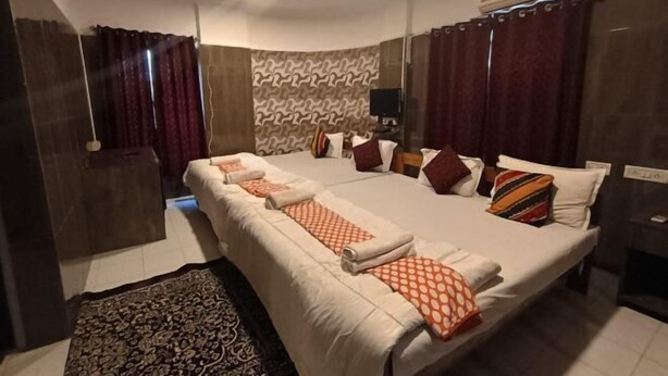 Une chambre d’hôtel avec un grand lit, un ventilateur de plafond, un appareil de climatisation et un tapis à motifs.